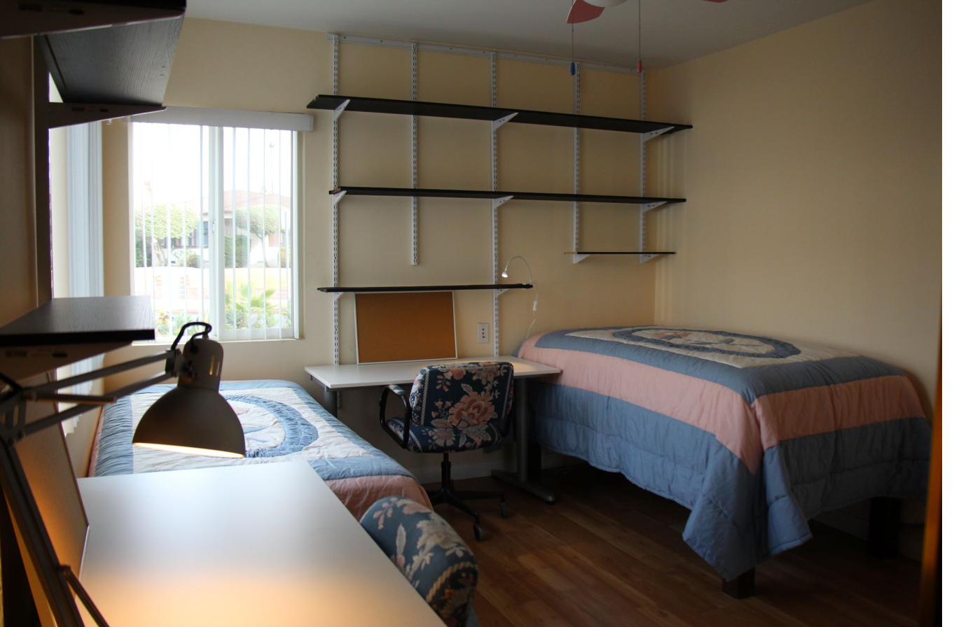 Furnished bedroom with natural light and shelving in CSULA student housing