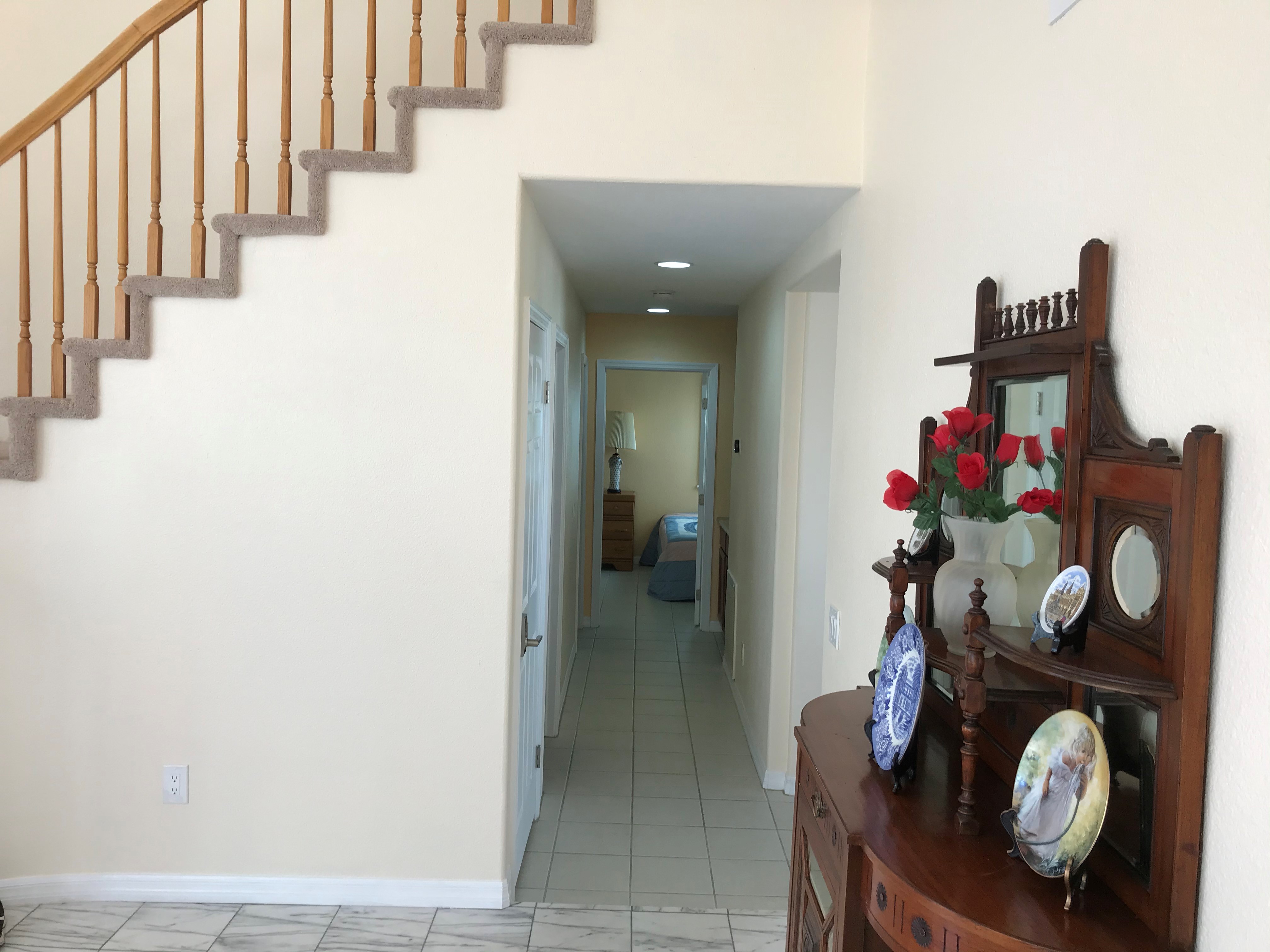 Downstairs hallway leading to bedroom with antique hutch in entry area