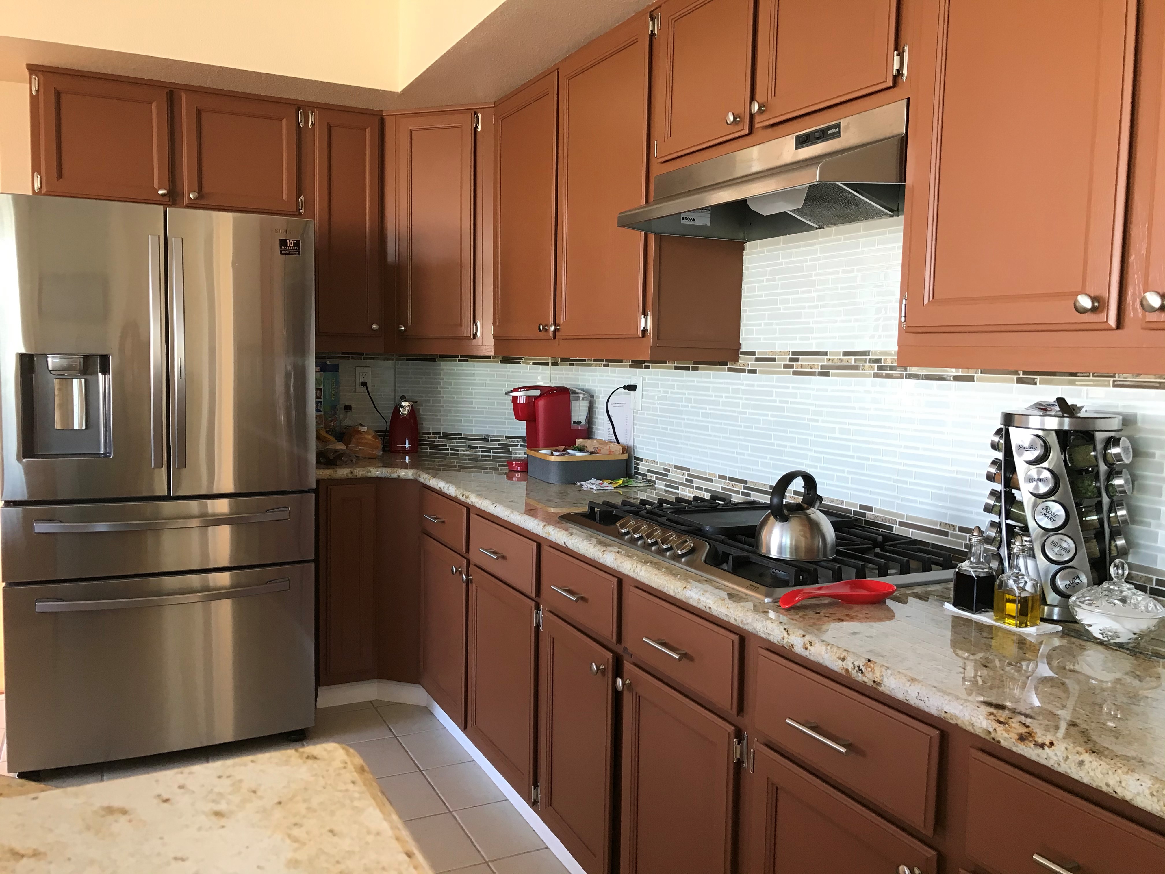 Kitchen close-up showing granite countertops, glass tile backsplash, and gas cooktop