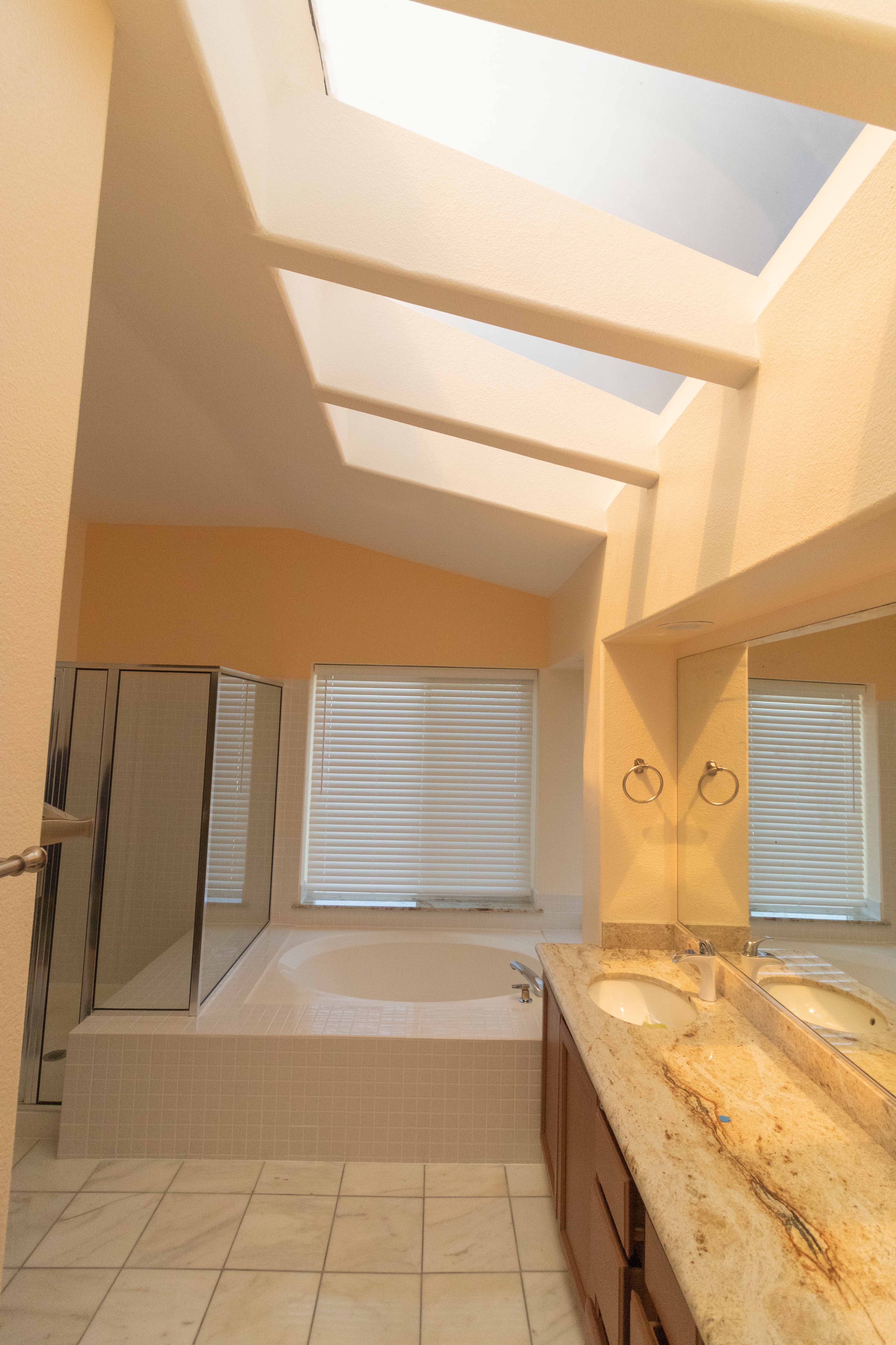 Master en-suite bathroom with dramatic skylights flooding natural light over soaking tub and double vanity