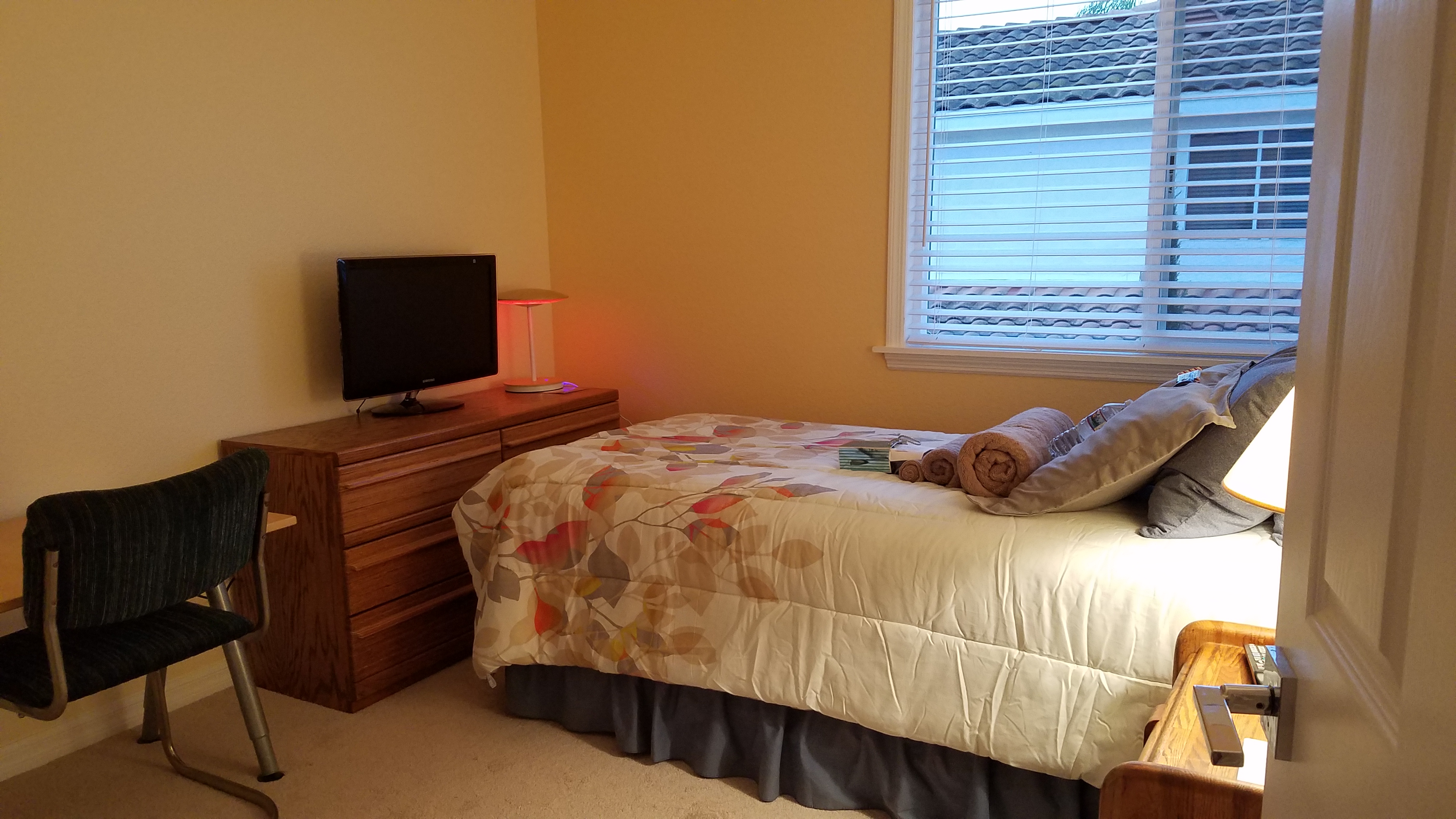 Furnished upstairs bedroom A with twin bed, blue geometric bedding, ornate headboard, desk, and TV
