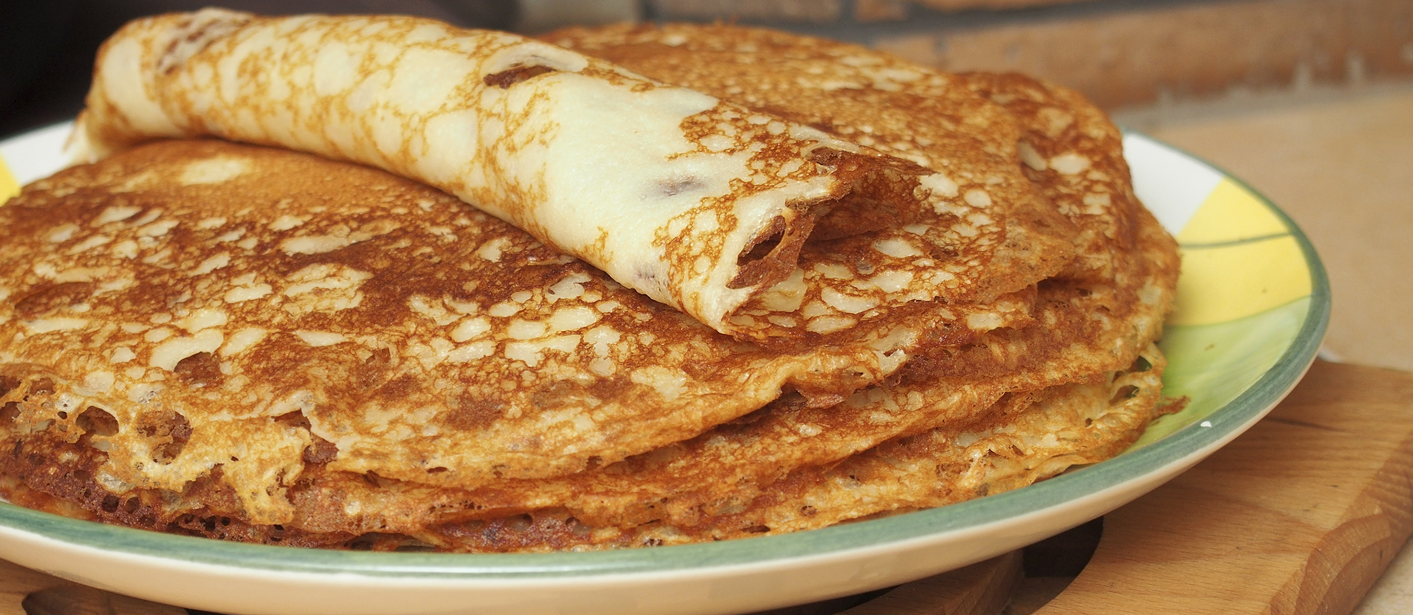 Stack of Polish naleśniki crepes, one rolled, on a plate